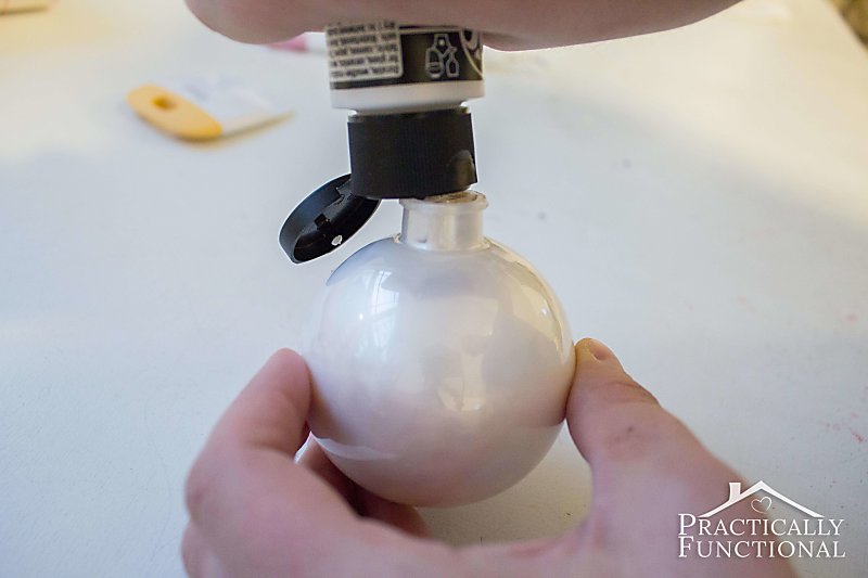 Fill a clear ornament with white paint to make a DIY snowman ornament